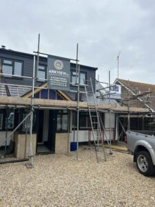 A chalet bungalow with building work in progress, showing scaffolding on the front with a porch being built