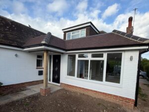 Closeup of bungalow facade with new porch, dormer window and front room with new windows.