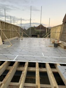 View from scaffolding of wooden floors and walls for a side extension.