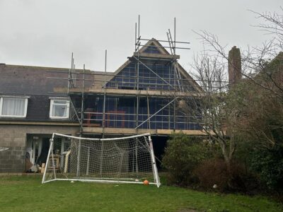 View from a garden of an extension being built, with scaffolding in place and membrane covering wooden frame.
