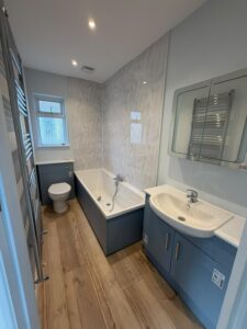 Remodelled bathroom with blue furniture and white bath, basin and toilet