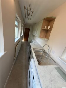 View of utility room with fitted appliances and a sink.