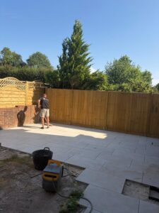 A tradesman cleaning a newly-fitted patio fitted with pale stone tiles.