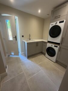 Spacious utility room with grey units and a two-storey washer/dryer within a fitted cupboard.