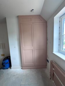Custom-built fitted wardrobe painted in a dusky pink