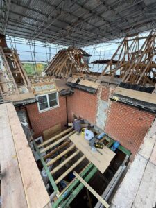 External view from scaffolding of workmen working on brickwork in a home extension